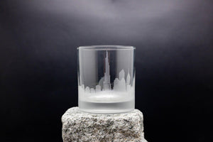 a glass on a rock with a city in the background