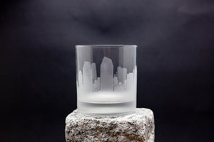 a glass on a rock with a city in the background