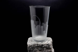 A clear glass with a city skyline printed on it, placed on a rock.