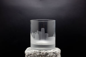 a glass on a rock with a city in the background