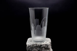 A frosted glass with a city skyline etched onto it, placed on a rock.