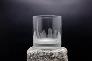 a glass on a rock with a city in the background