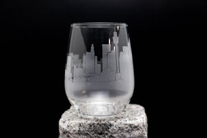 A frosted glass with a city skyline printed on it, placed on a rock.