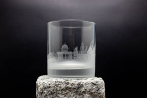 a glass on a rock with a building in the background