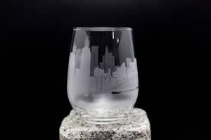 A frosted glass with a city skyline etched onto it, set against a dark background.
