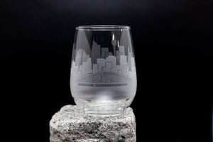 A frosted glass with a cityscape design etched onto it, placed on a rock.