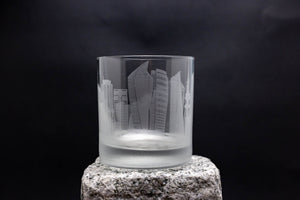 a glass on a rock with a city skyline etched on it