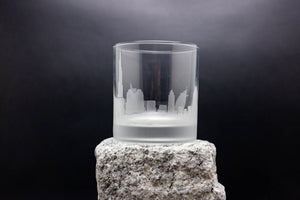 a glass on a rock with a city in the background