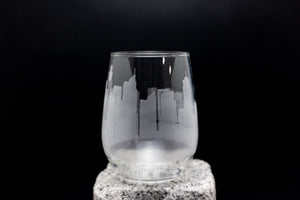 A frosted glass with a city skyline etched onto it, set against a dark background.