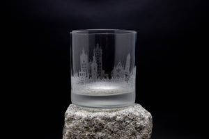 a glass on a rock with a city in the background