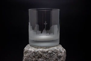 a glass on a rock with a city skyline in the background